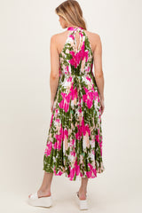 woman wearing a floral maternity dress with a halter neck and pleated skirt, featuring pink and green colors
