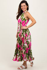 woman wearing a floral pleated maxi dress with pink and green hues, posing with one hand on her hip