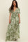 woman wearing a green floral maxi dress with puff sleeves and a tie front detail
