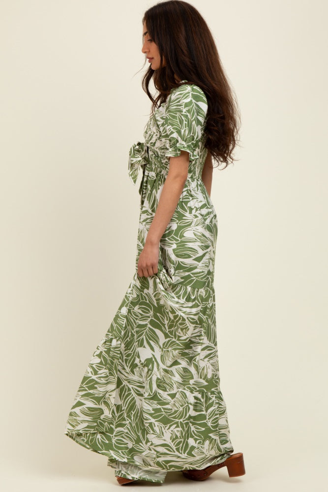 woman wearing a green floral maxi dress with short sleeves and a tied waist detail