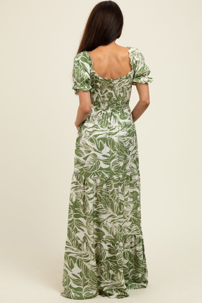 woman wearing a backless green floral maxi dress with puff sleeves and a tiered skirt