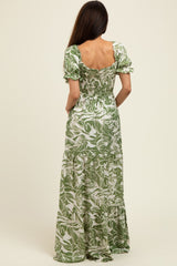 woman wearing a backless green floral maxi dress with puff sleeves and a tiered skirt