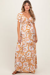 woman wearing a floral print maternity maxi dress with puff sleeves and a tied front detail, showcasing her baby bump