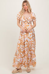 woman wearing a floral print maxi dress with short puff sleeves and a front tie detail, paired with platform sandals