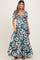 woman wearing a floral print maternity maxi dress with a tie detail and puff sleeves, showcasing her baby bump