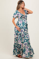 woman wearing a floral maternity maxi dress with a fitted bodice and ruffled sleeves, cradling her baby bump