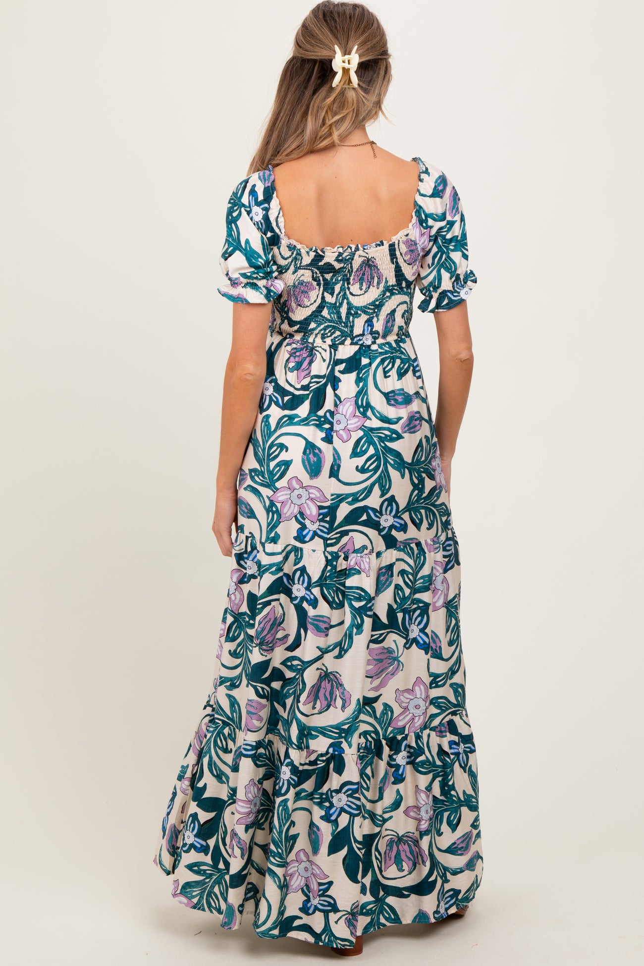 woman wearing a floral print maternity maxi dress with short puff sleeves and a smocked bodice, shown from the back