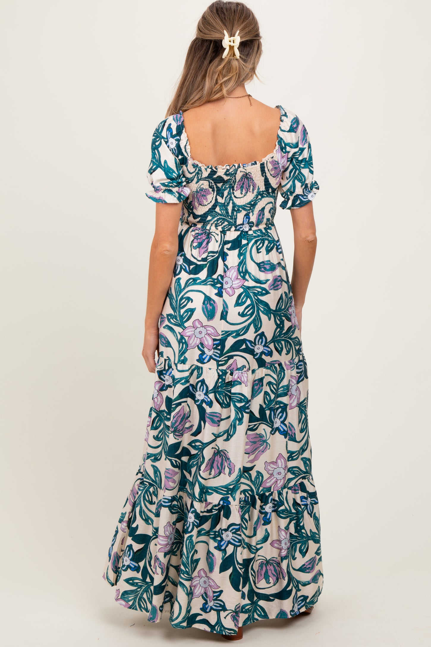 woman wearing a floral print maternity maxi dress with short puff sleeves and a smocked bodice, shown from the back