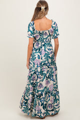 woman wearing a floral print maternity maxi dress with short puff sleeves and a smocked bodice, shown from the back