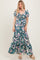woman wearing a floral maxi dress with puff sleeves and a tie front detail, standing on a light background
