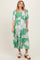 woman wearing a green floral mid-length dress with puff sleeves and a smocked bodice, standing against a neutral background