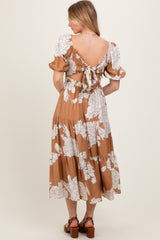 woman wearing a brown floral midi dress with puff sleeves and a tied back detail, showing the back view