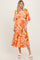 woman wearing a bright orange floral maxi dress with ruffled sleeves and a tiered skirt