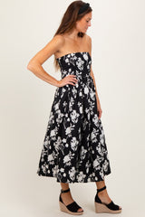 woman wearing a black strapless floral midi dress with a fitted bodice and full skirt, paired with wedge heels