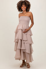 woman wearing a strapless blush maternity maxi dress with layered ruffles and holding her baby bump