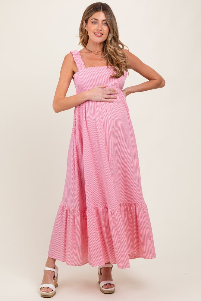 woman wearing a pink striped maternity maxi dress with ruffle straps and a baby bump visible