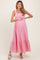 woman wearing a pink striped maternity maxi dress with ruffle straps and a baby bump visible