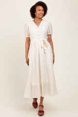 woman wearing a cream long sleeve button-up maxi dress with puff sleeves and a tie waist detail