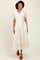 woman wearing a cream long sleeve button-up maxi dress with puff sleeves and a tie waist detail
