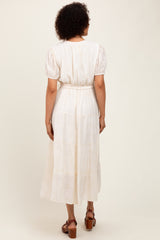 woman wearing a white tiered midi dress with puff sleeves and a belted waist, viewed from the back