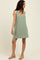 woman wearing a casual light green sleeveless tunic dress with a v-neckline and side slits, styled with nude sandals
