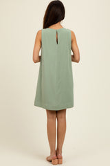 woman wearing a mint green sleeveless shift dress with a keyhole back detail