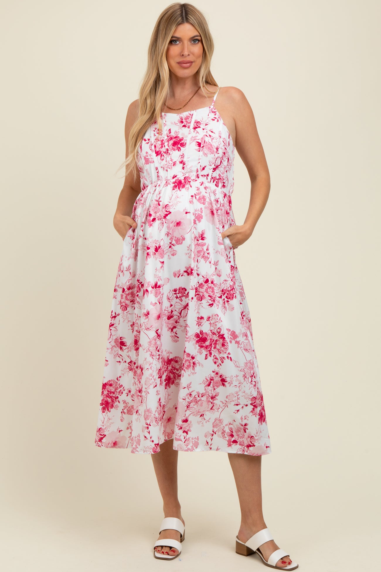 woman wearing a floral pink and white maternity dress with pockets and a baby bump visible