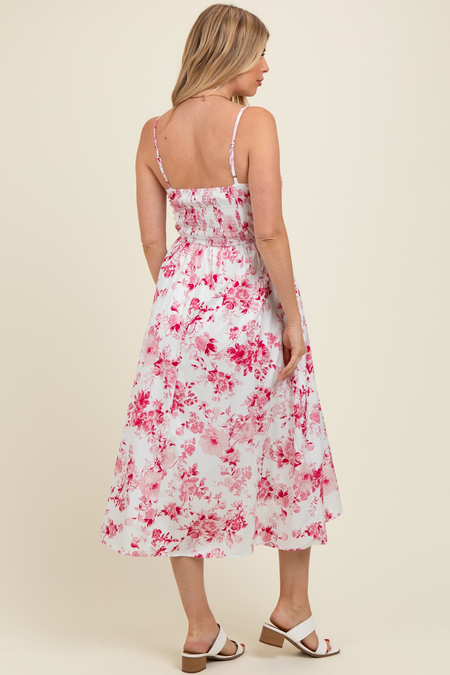 woman wearing a pink floral maternity dress with a smocked back and spaghetti straps