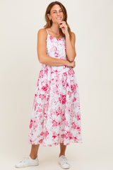 woman wearing a white floral midi dress with pink patterns and white sneakers
