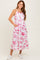 woman wearing a white floral midi dress with pink patterns and pockets, paired with white sneakers
