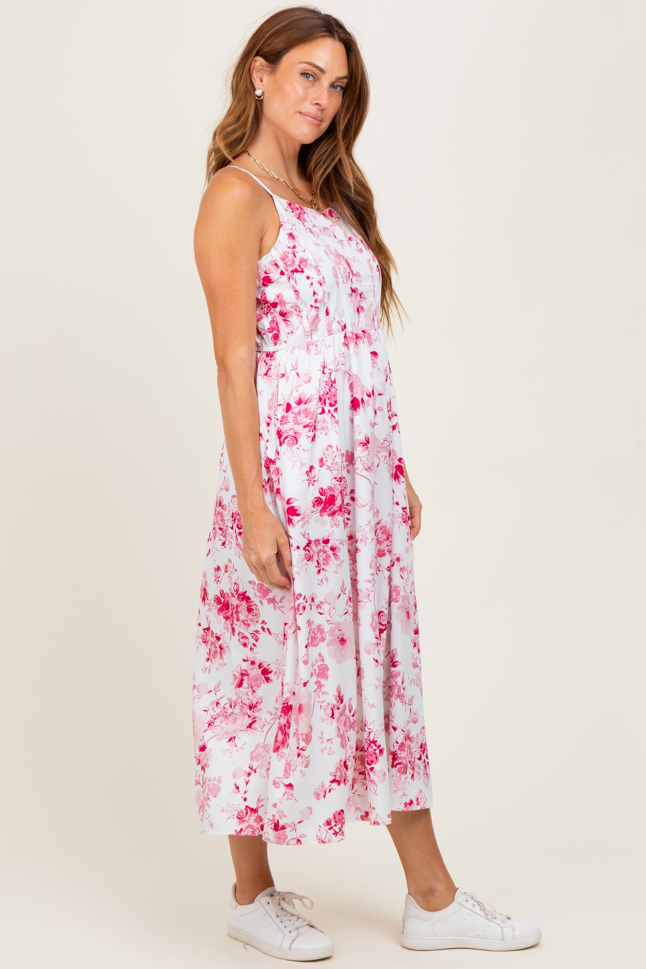 woman wearing a white floral midi dress with pink flowers and paired with white sneakers