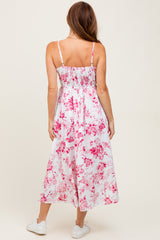 woman wearing a white floral maxi dress with pink patterns and spaghetti straps, seen from the back