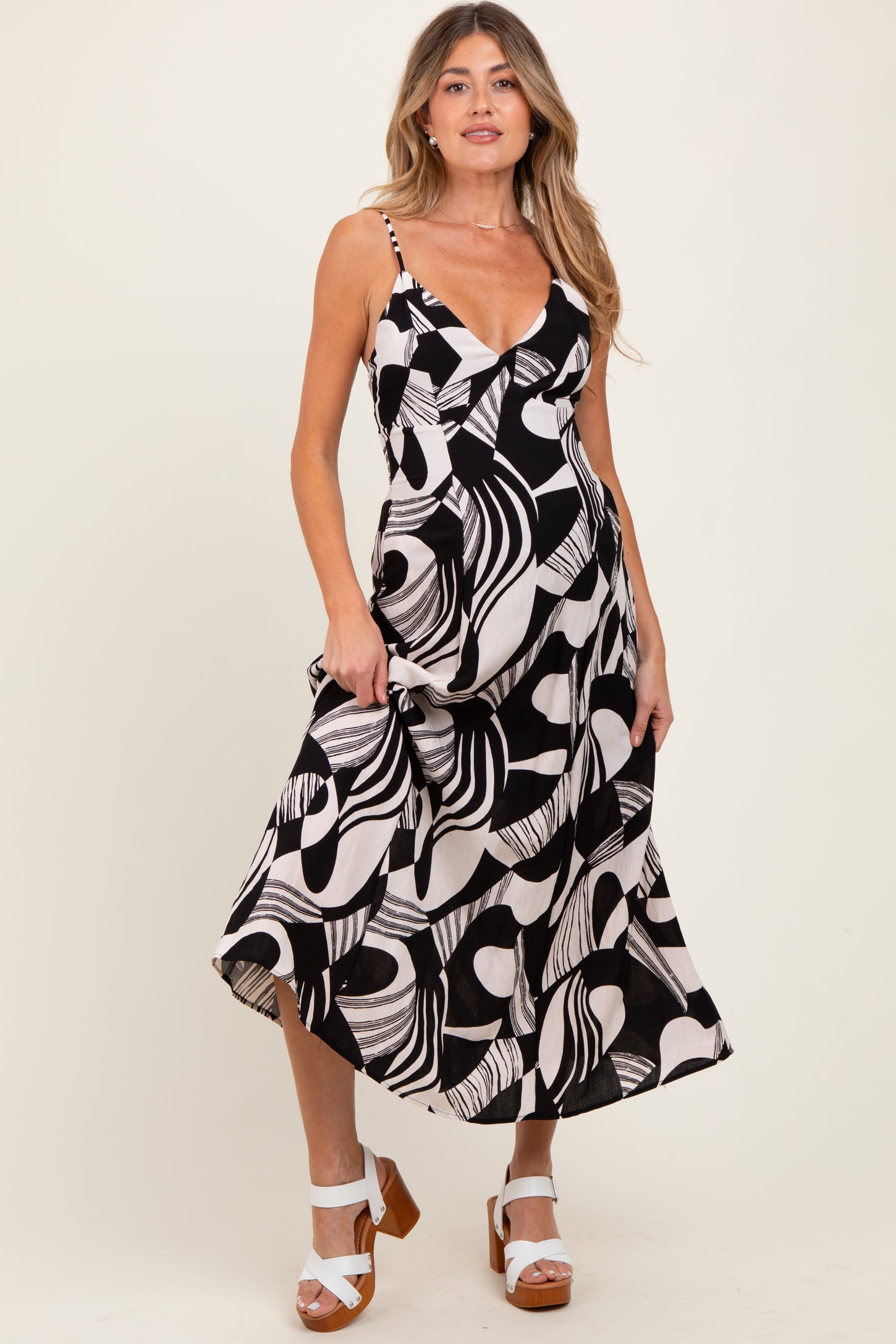 woman wearing a black and white abstract print maternity dress with a v-neck and spaghetti straps