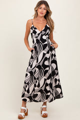 woman wearing a black and white abstract patterned maternity dress with pockets and spaghetti straps
