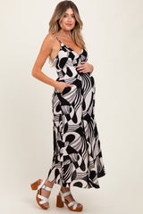 woman wearing a black and white patterned maternity maxi dress and holding her baby bump
