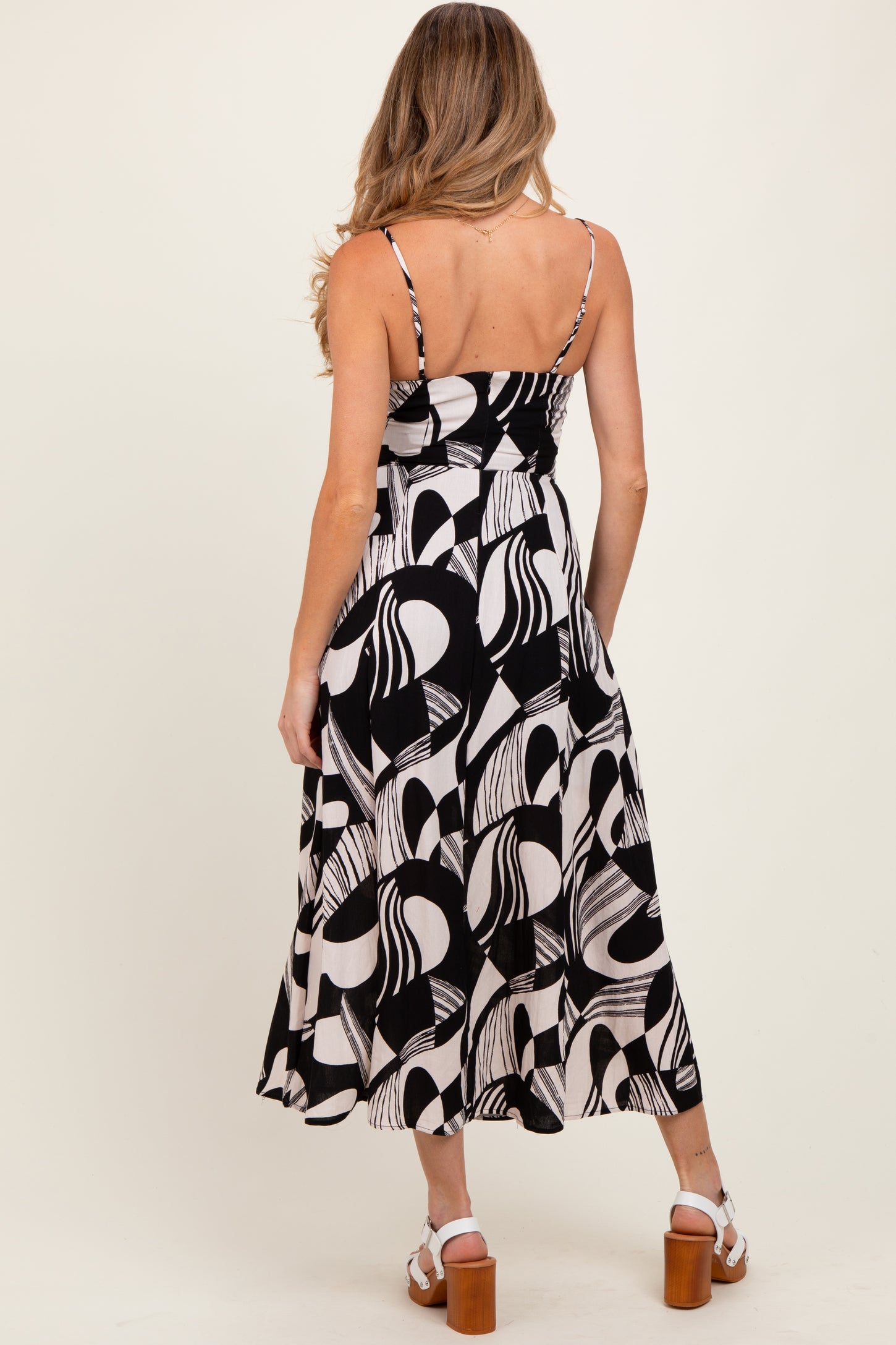 woman wearing a black and white patterned maternity dress with adjustable straps and a flared skirt