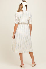 woman wearing a light floral print maternity dress with short puff sleeves and a cinched waist, seen from the back