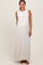 woman wearing a light beige maternity maxi dress with ruffled straps and side pockets, standing in a relaxed pose