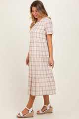 woman wearing a beige plaid tiered midi dress with short sleeves and a flared skirt, paired with white wedge sandals