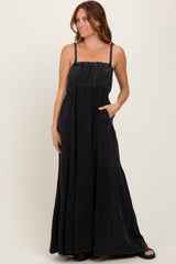woman wearing a black tiered maxi dress with adjustable straps and pockets