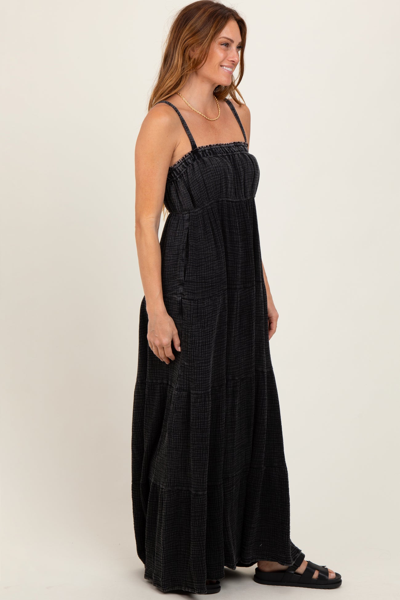 woman wearing a black tiered maxi dress with adjustable straps and a relaxed fit