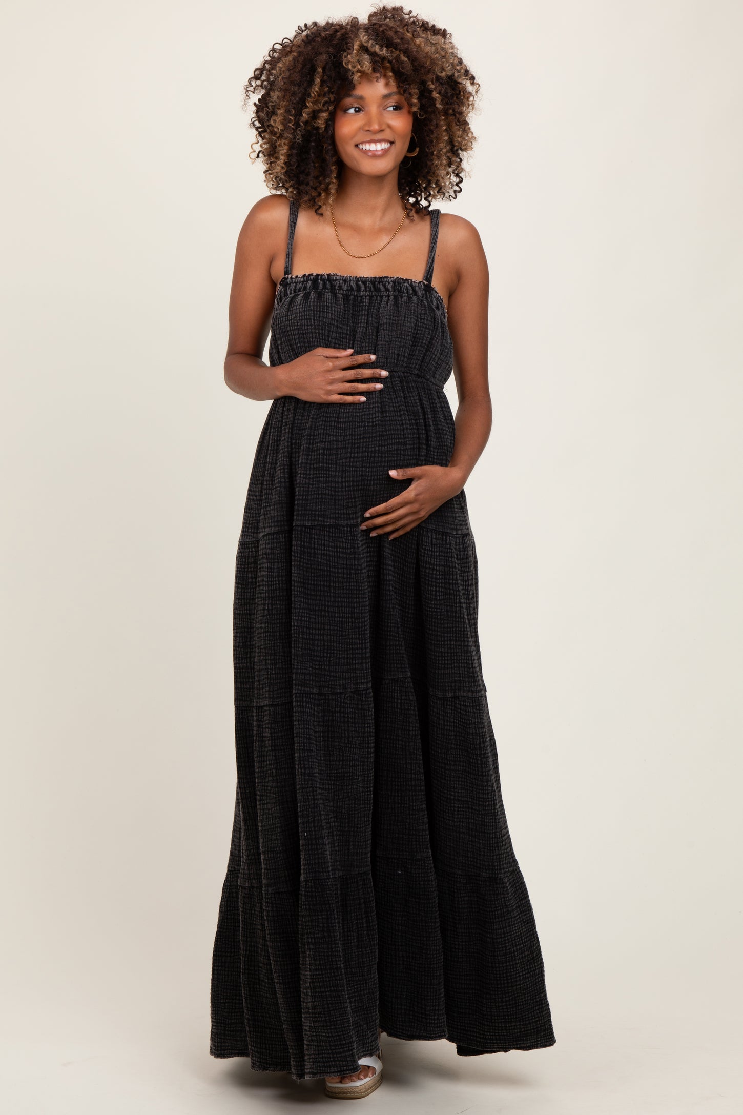woman wearing a black tiered maxi maternity dress and holding her baby bump