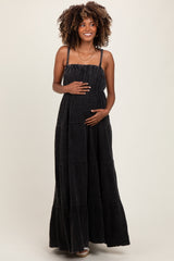 woman wearing a black tiered maxi maternity dress and holding her baby bump