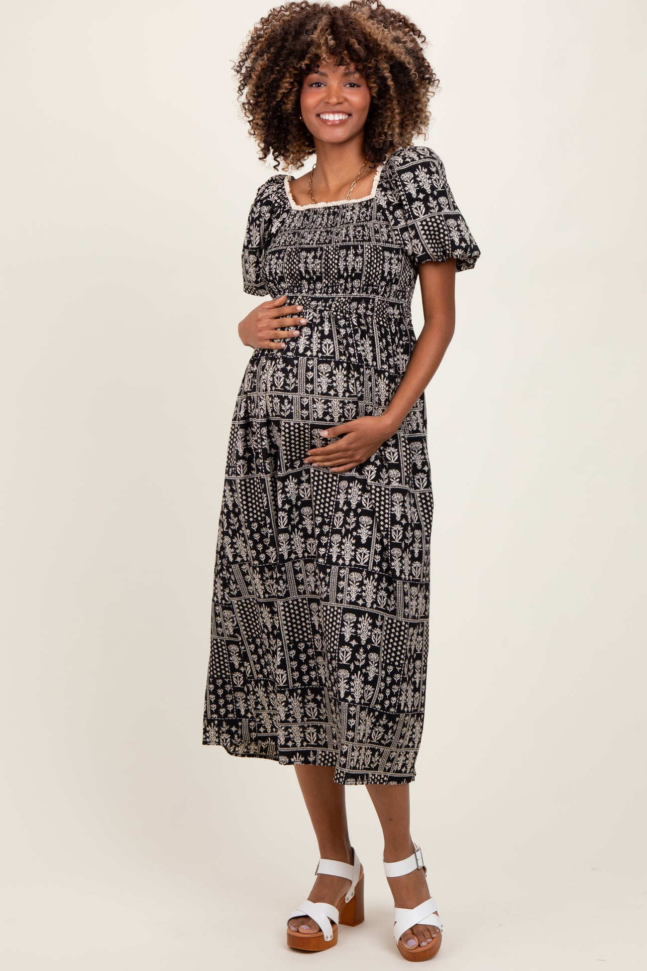 woman wearing a black and white patterned maternity dress with puff sleeves and a baby bump