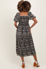 woman wearing a black and white patterned maternity maxi dress with puff sleeves, showing the back view