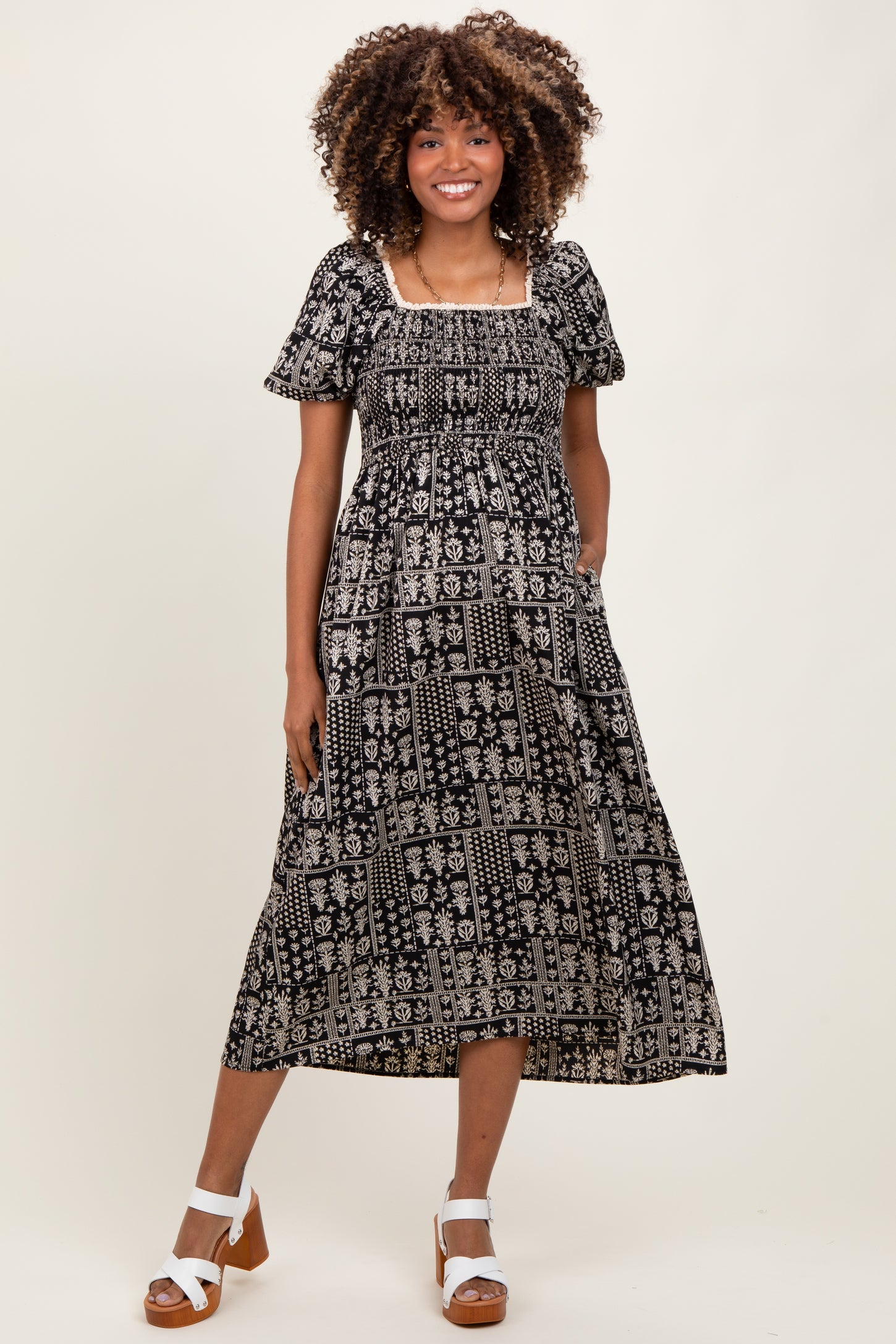 woman wearing a black and white floral print maternity dress with short puff sleeves and a square neckline