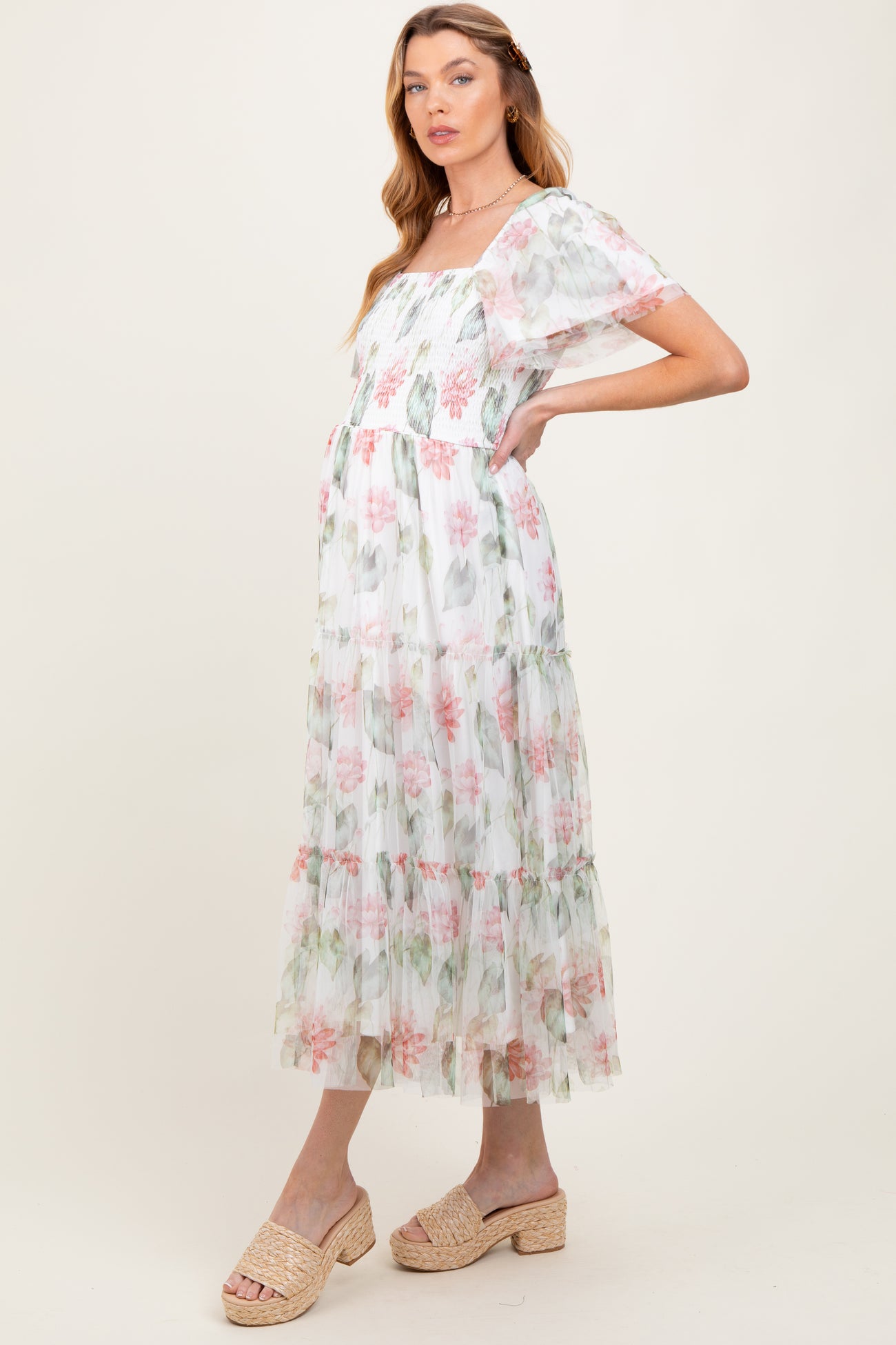 woman wearing a floral print maternity maxi dress with tiered ruffles and short sheer sleeves, showcasing her baby bump