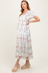 woman wearing a floral print maternity maxi dress with tiered ruffles and short sheer sleeves, showcasing her baby bump