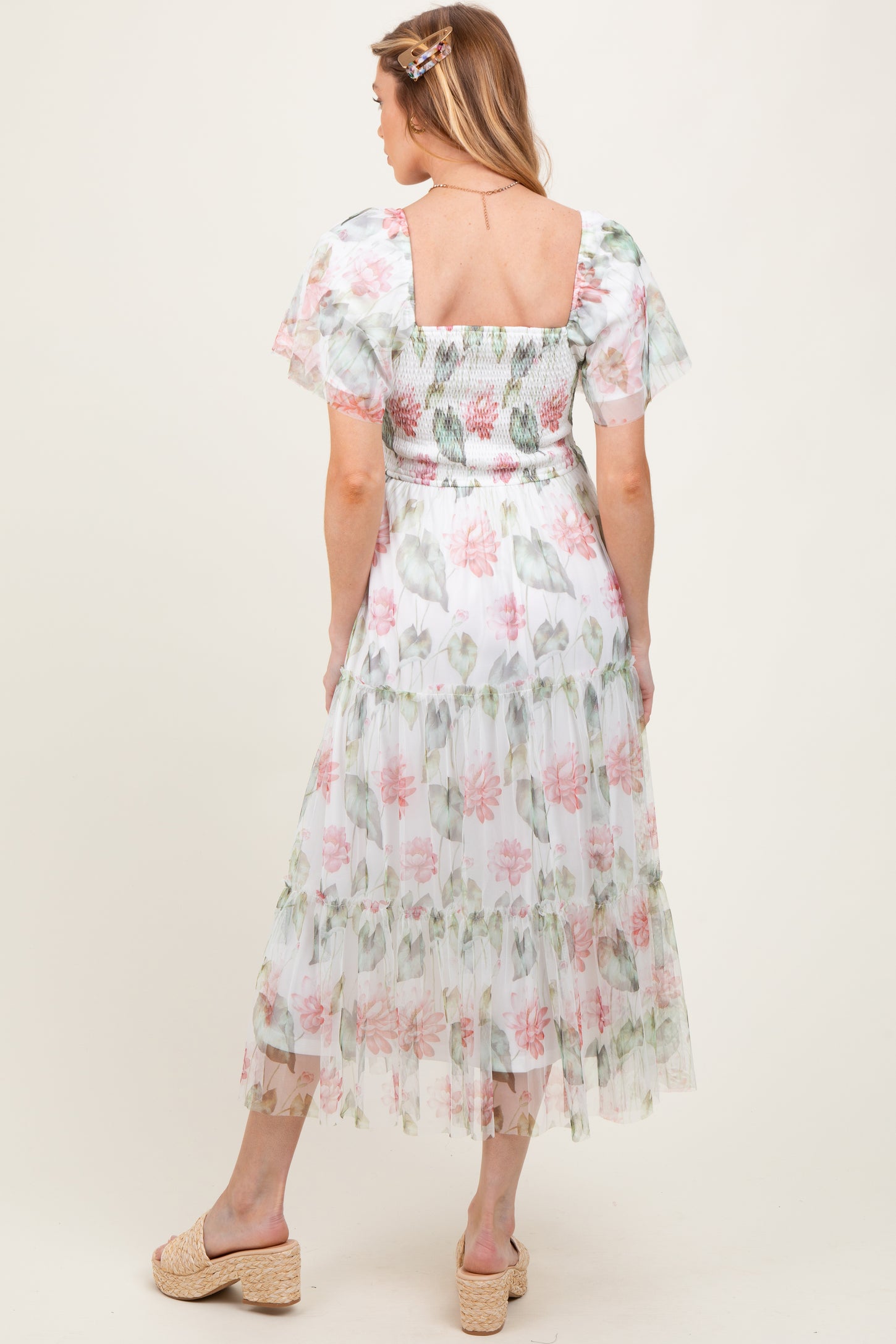 woman wearing a floral maternity maxi dress with puff sleeves and a smocked bodice, showing a baby bump from the back