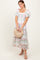 woman wearing a floral midi dress with puff sleeves and a square neckline, holding a woven clutch bag